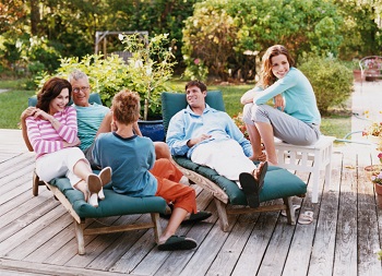 Three Generational Family Sit on Decking in Their Garden