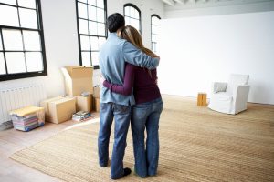 Couple embracing, standing indoors, rear view