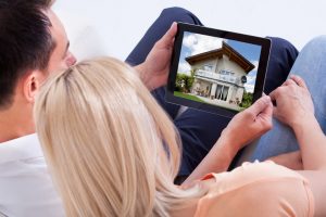 Couple Looking At House On Digital Tablet's Screen