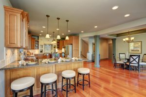 Luxury kitchen room interior with cabinets and granite counter tops. Bar counter with elegant pendant lights and dinner setting. Northwest, USA